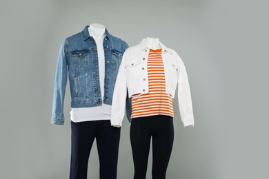 Female and male mannequins with stylish outfits on light grey background