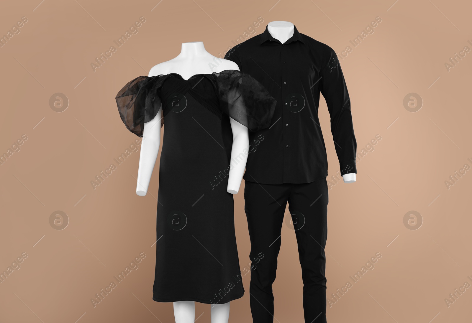 Photo of Female and male mannequins with stylish outfits on light brown background