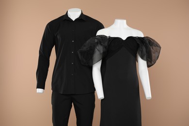 Photo of Female and male mannequins with stylish outfits on light brown background