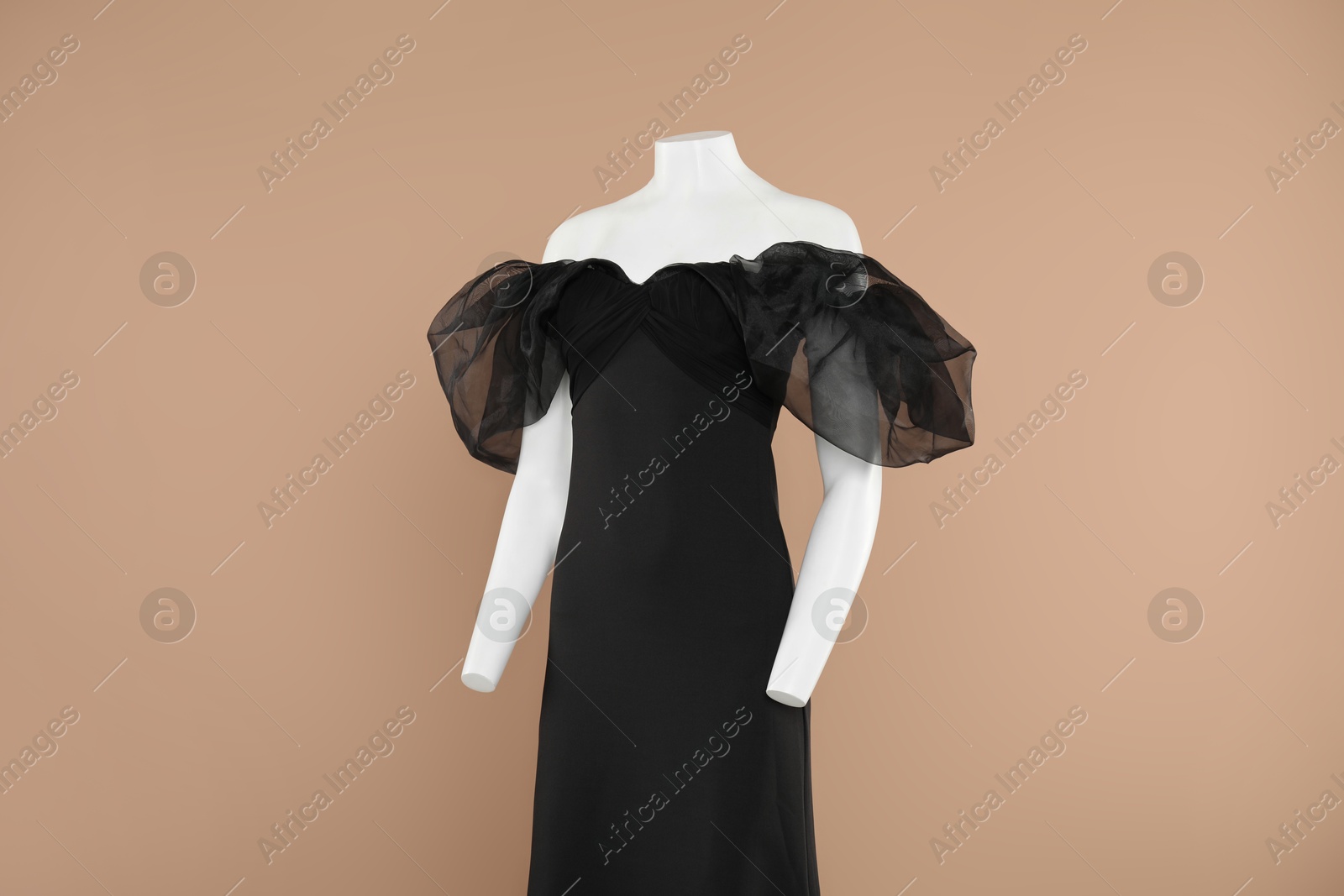 Photo of Female mannequin with stylish dress on light brown background, space for text