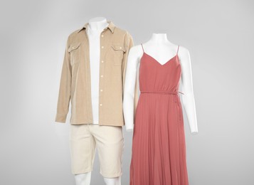 Photo of Female and male mannequins with stylish outfits on light grey background