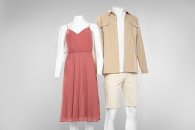 Photo of Female and male mannequins with stylish outfits on light grey background