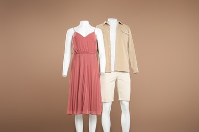 Photo of Female and male mannequins with stylish outfits on light brown background