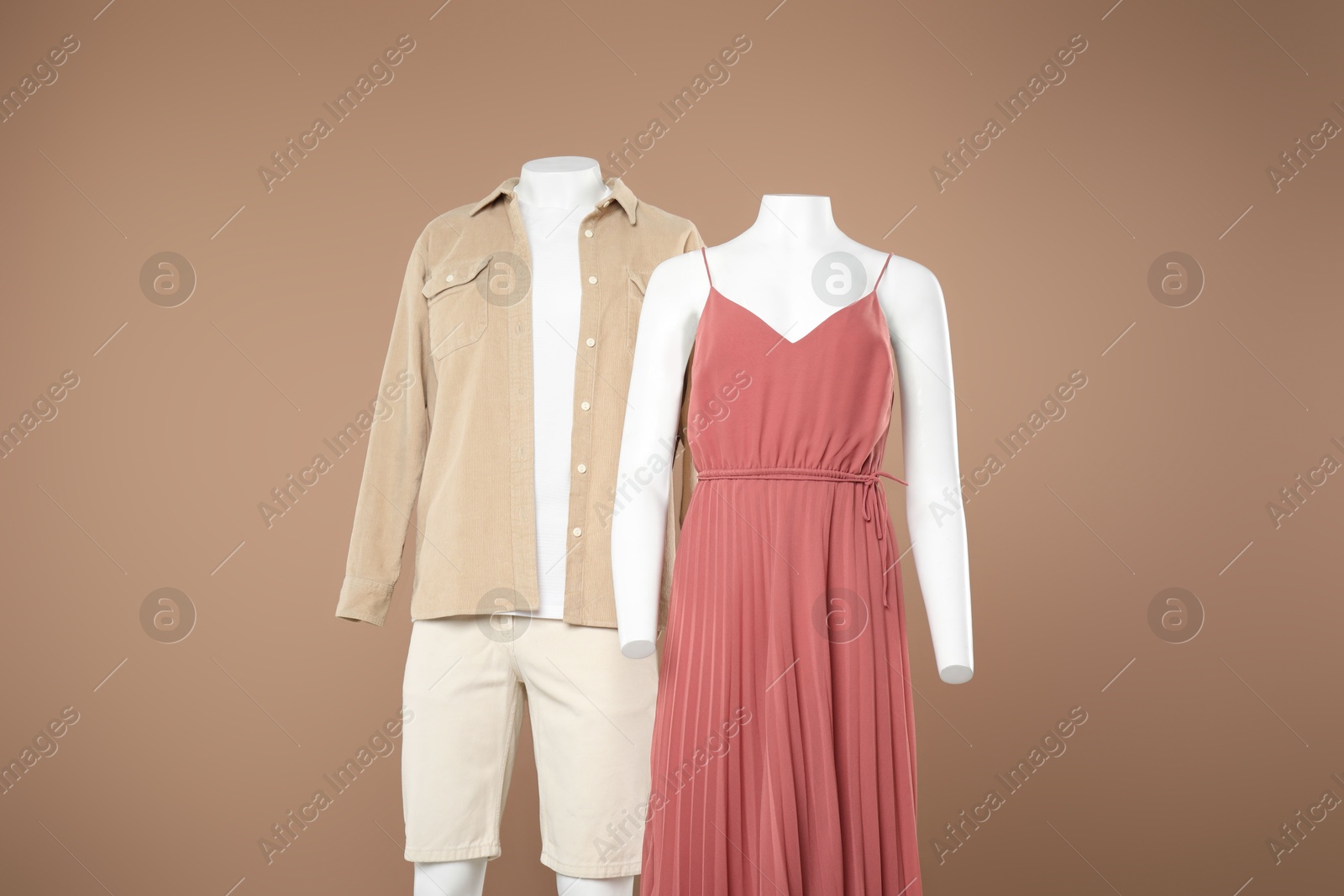 Photo of Female and male mannequins with stylish outfits on light brown background