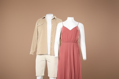 Female and male mannequins with stylish outfits on light brown background