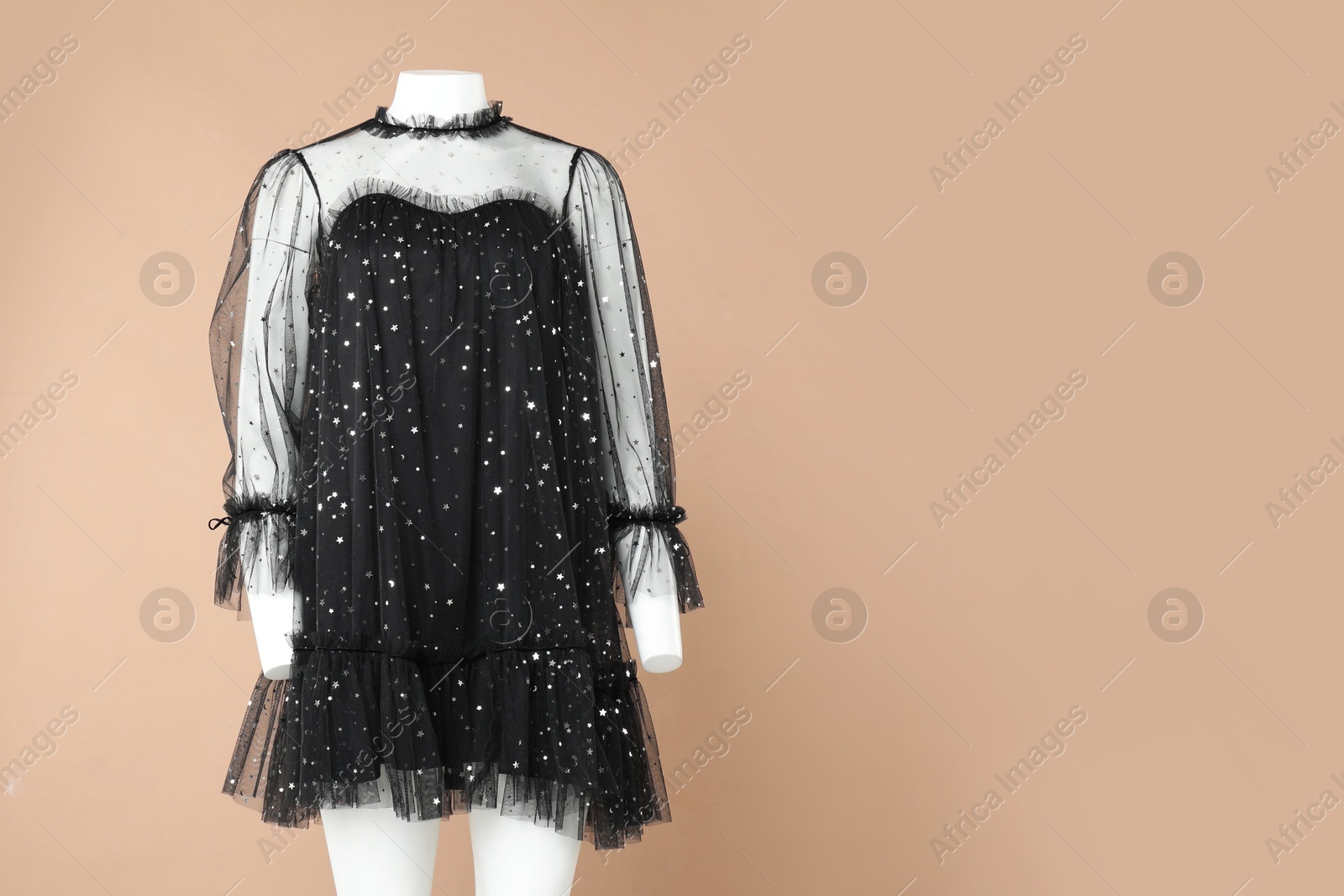 Photo of Female mannequin with stylish dress on light brown background, space for text