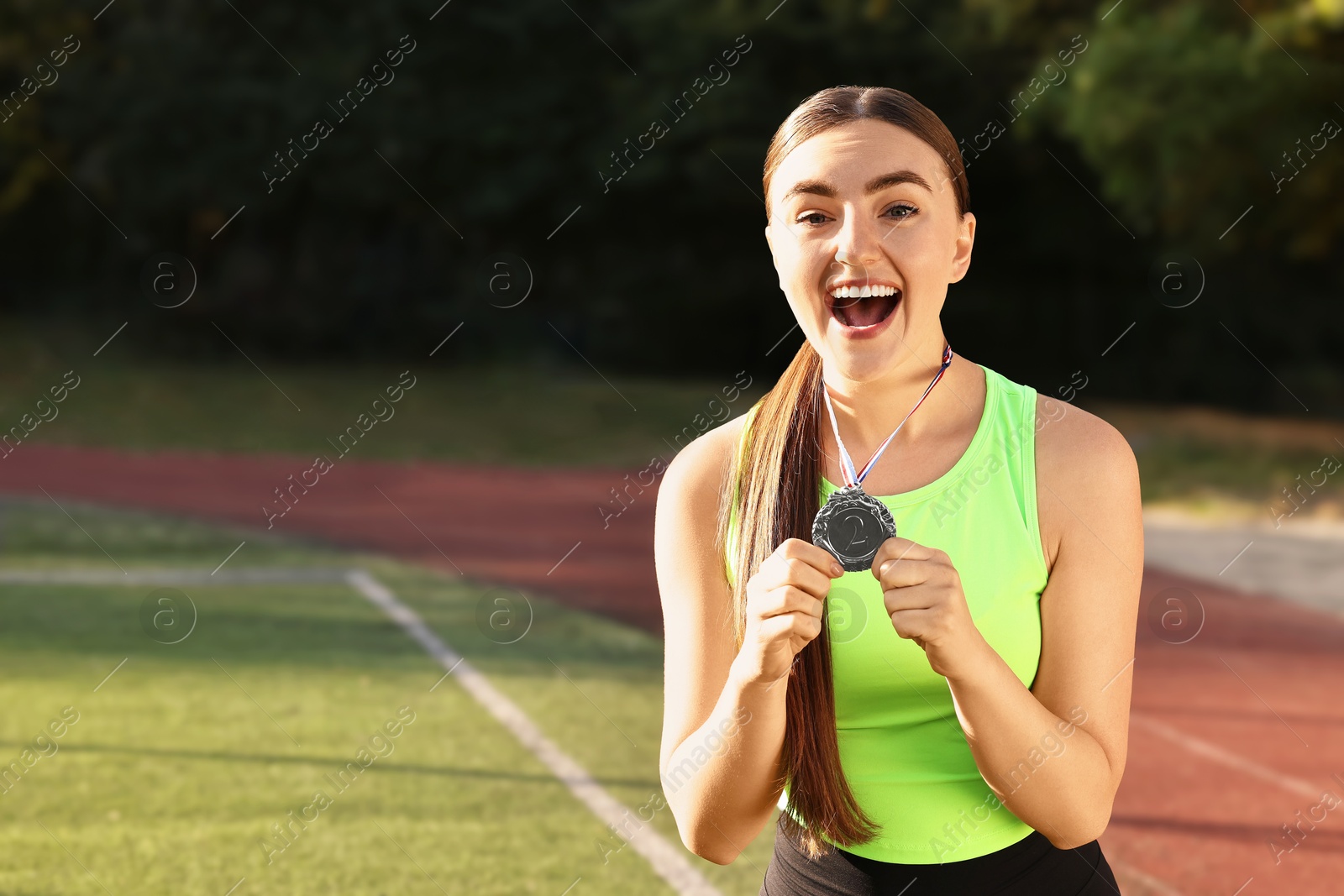 Photo of Happy winner with silver medal at stadium. Space for text