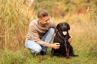 Photo of Smiling man with cute dog outdoors on autumn day