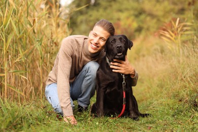 Photo of Smiling man with cute dog outdoors on autumn day