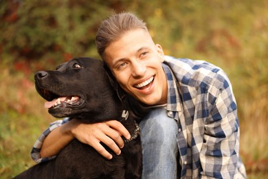 Photo of Smiling man with cute dog outdoors on autumn day