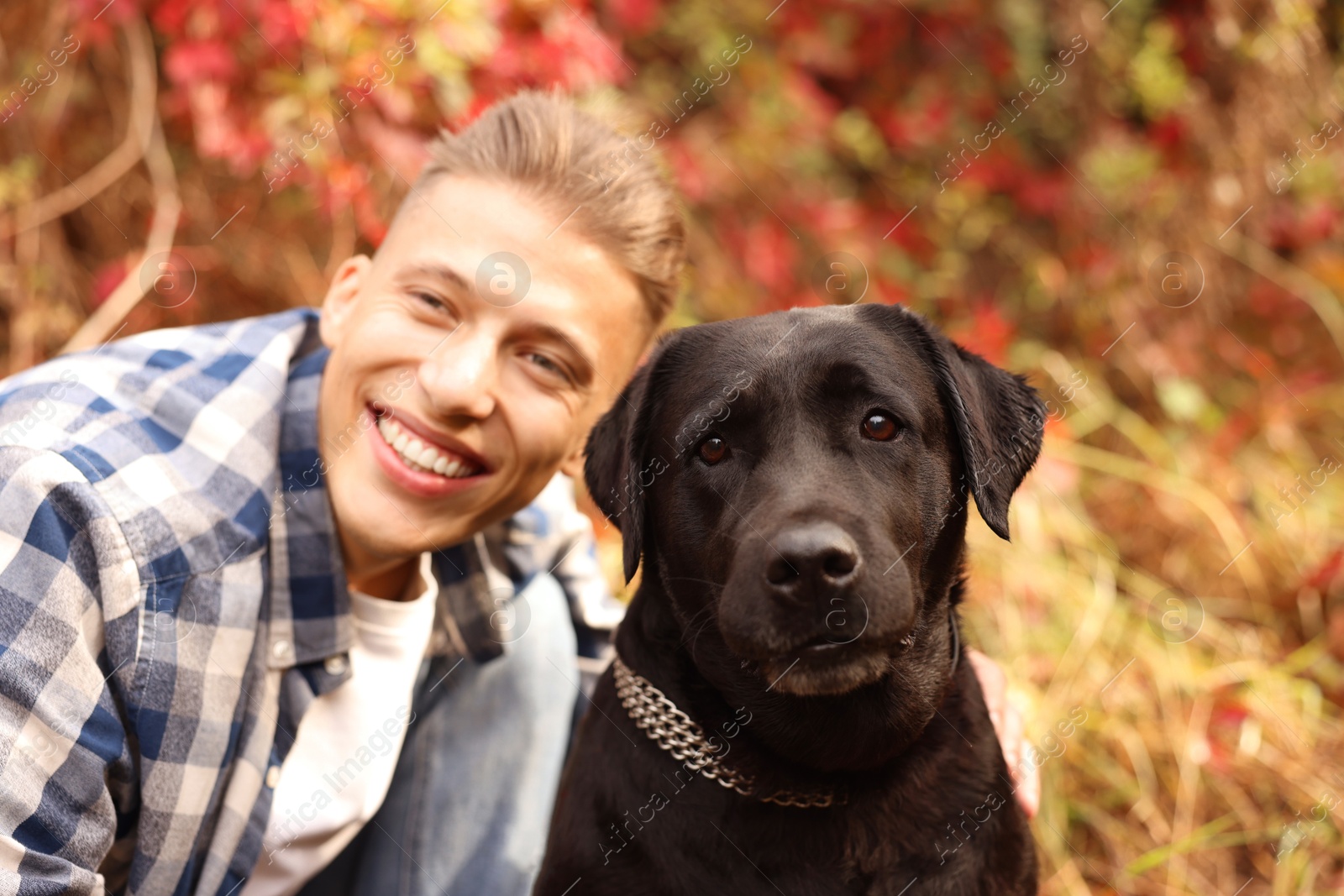 Photo of Smiling man with cute dog outdoors on autumn day