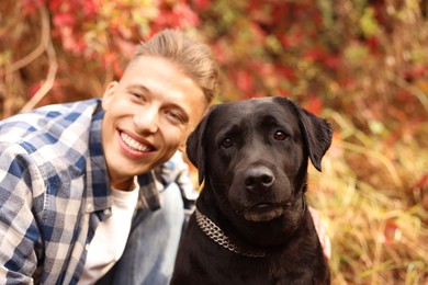 Photo of Smiling man with cute dog outdoors on autumn day