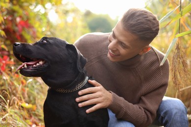 Smiling man with cute dog outdoors on autumn day