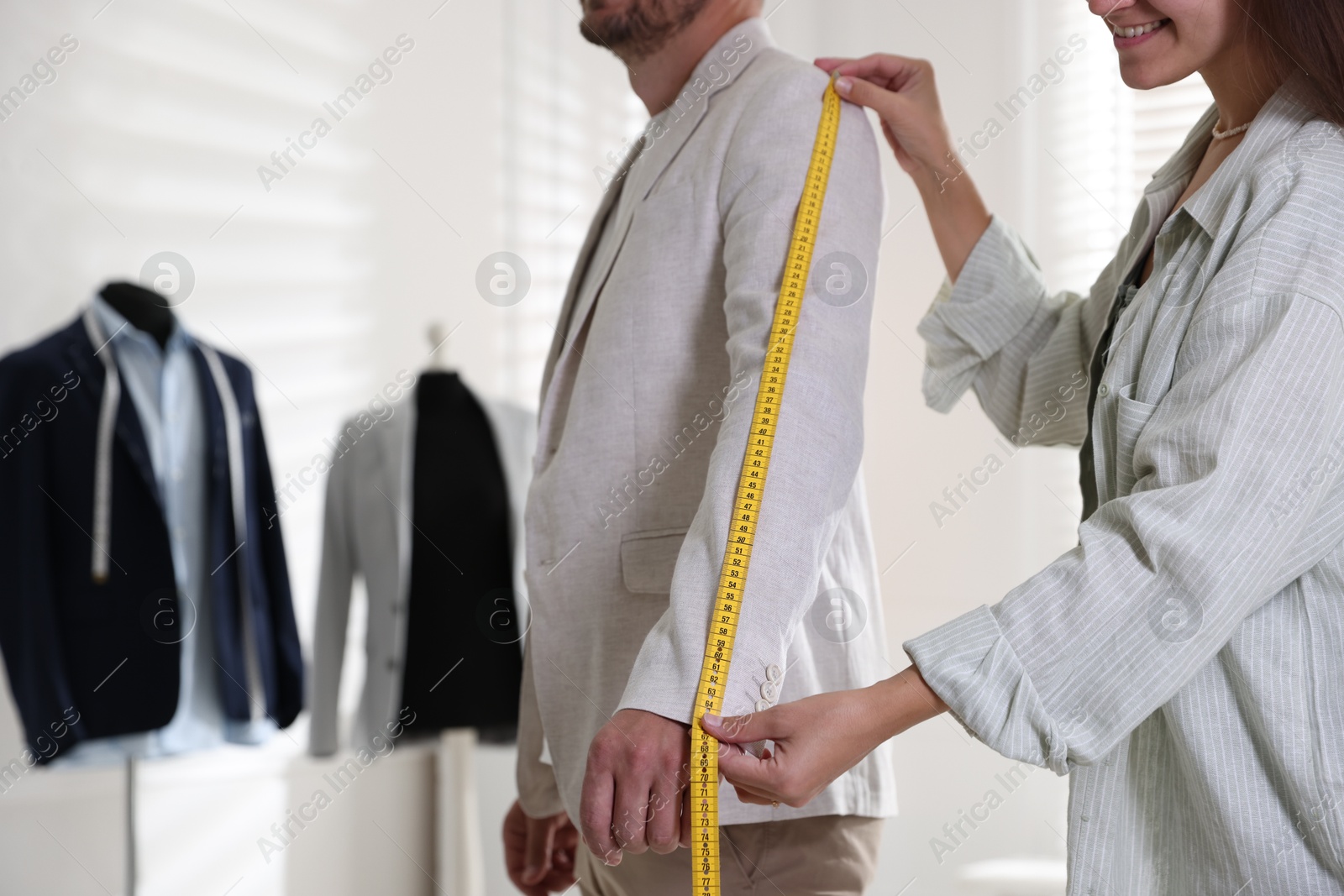 Photo of Woman measuring sleeve on man in atelier, closeup