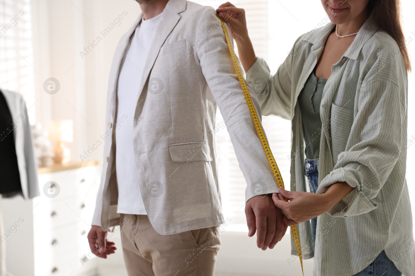 Photo of Woman measuring sleeve on man in atelier, closeup