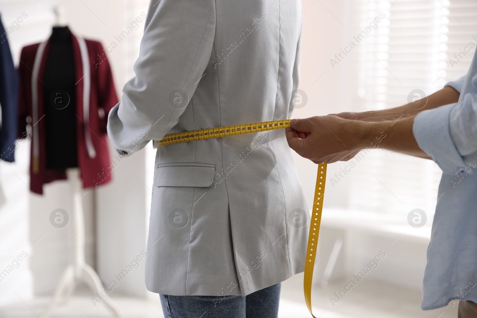 Photo of Man measuring woman's waist with tape in atelier, closeup