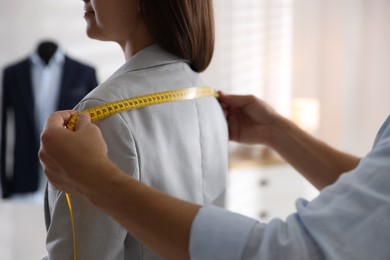 Man measuring woman's shoulders with tape in atelier, closeup