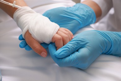 Photo of Doctor and child with IV drip in hospital, closeup