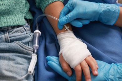 Photo of Doctor and child with IV drip in hospital, closeup