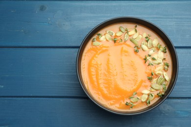 Photo of Delicious sweet potato soup with pumpkin seeds on blue wooden table, top view. Space for text