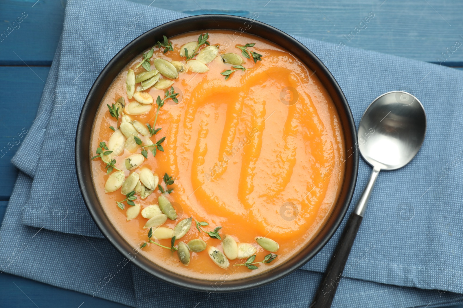 Photo of Delicious sweet potato soup with pumpkin seeds on blue wooden table, top view