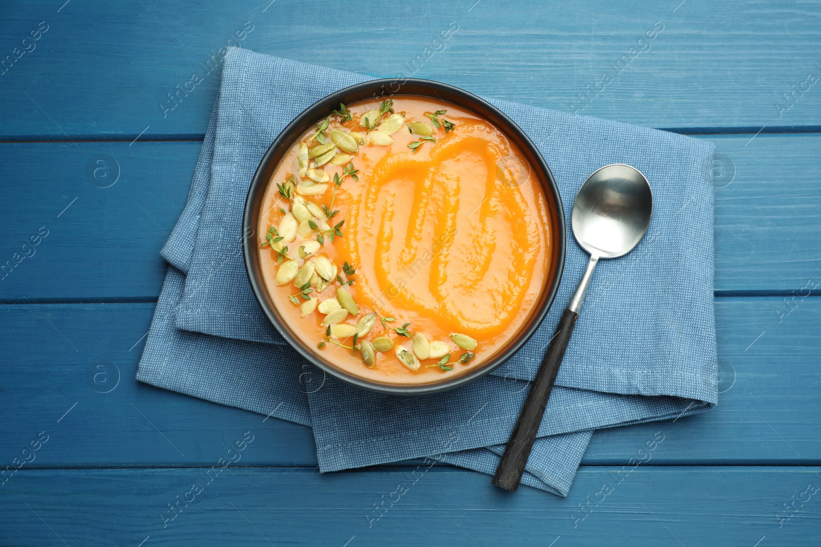 Photo of Delicious sweet potato soup with pumpkin seeds on blue wooden table, top view