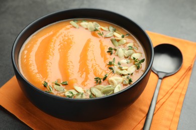 Photo of Delicious sweet potato soup with pumpkin seeds in bowl on grey table, closeup