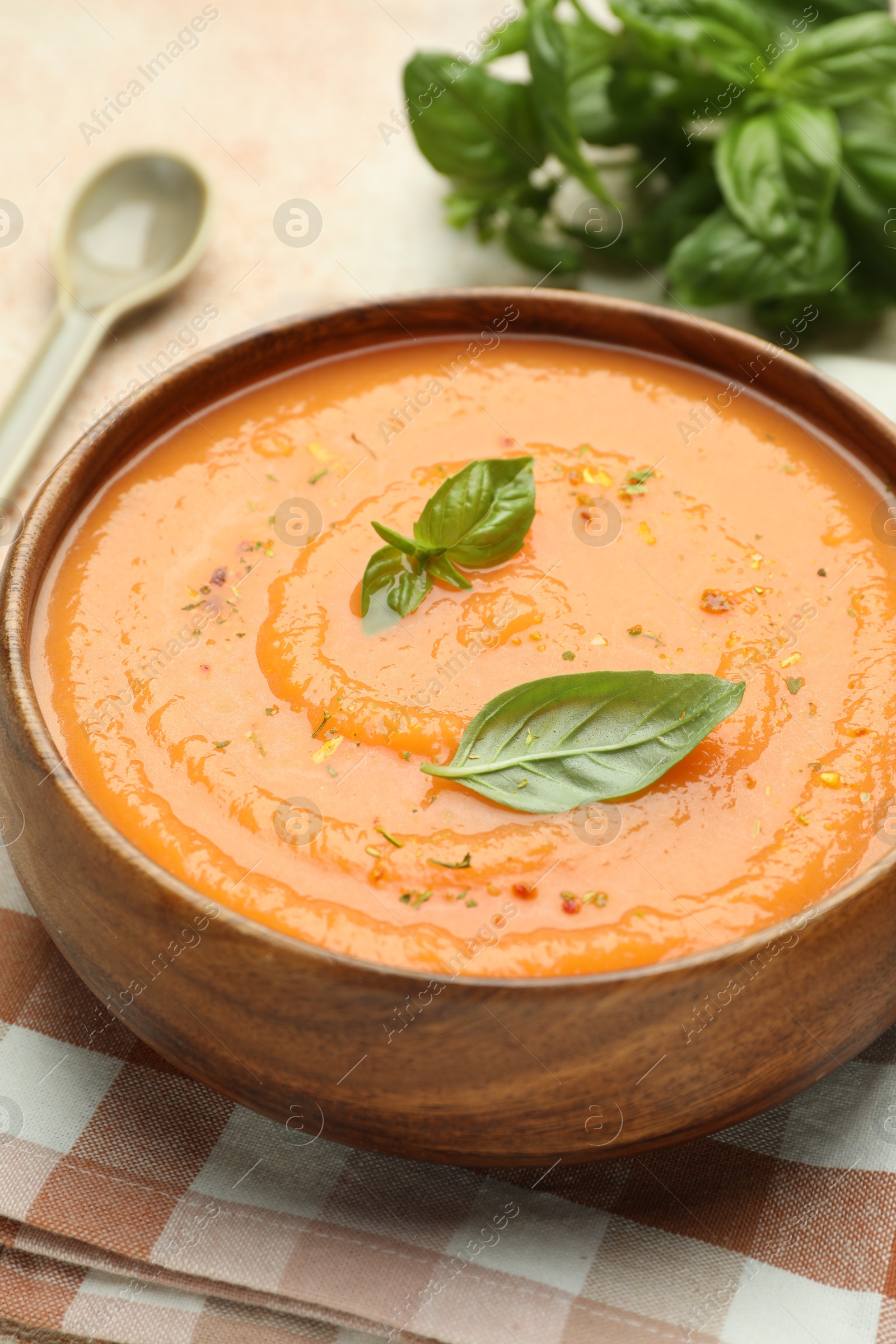 Photo of Delicious sweet potato soup with spices and basil in bowl on table, closeup