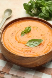 Photo of Delicious sweet potato soup with spices and basil in bowl on table, closeup