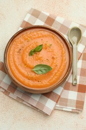 Photo of Delicious sweet potato soup with spices and basil on beige textured table, top view