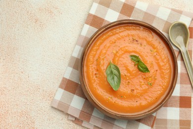 Photo of Delicious sweet potato soup with spices and basil on beige textured table, top view. Space for text