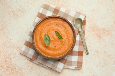 Photo of Delicious sweet potato soup with spices and basil on beige textured table, top view