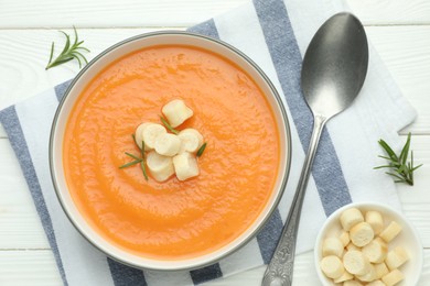 Photo of Delicious sweet potato soup with croutons on white wooden table, top view