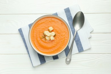 Photo of Delicious sweet potato soup with croutons on white wooden table, top view