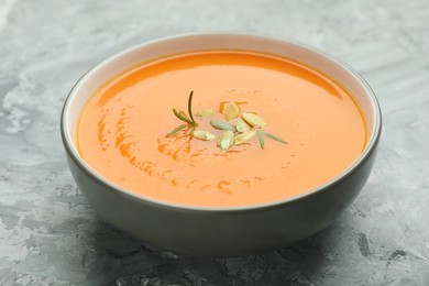 Photo of Delicious sweet potato soup with pumpkin seeds on grey textured table, closeup