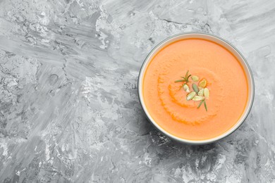 Photo of Delicious sweet potato soup with pumpkin seeds on grey textured table, top view. Space for text