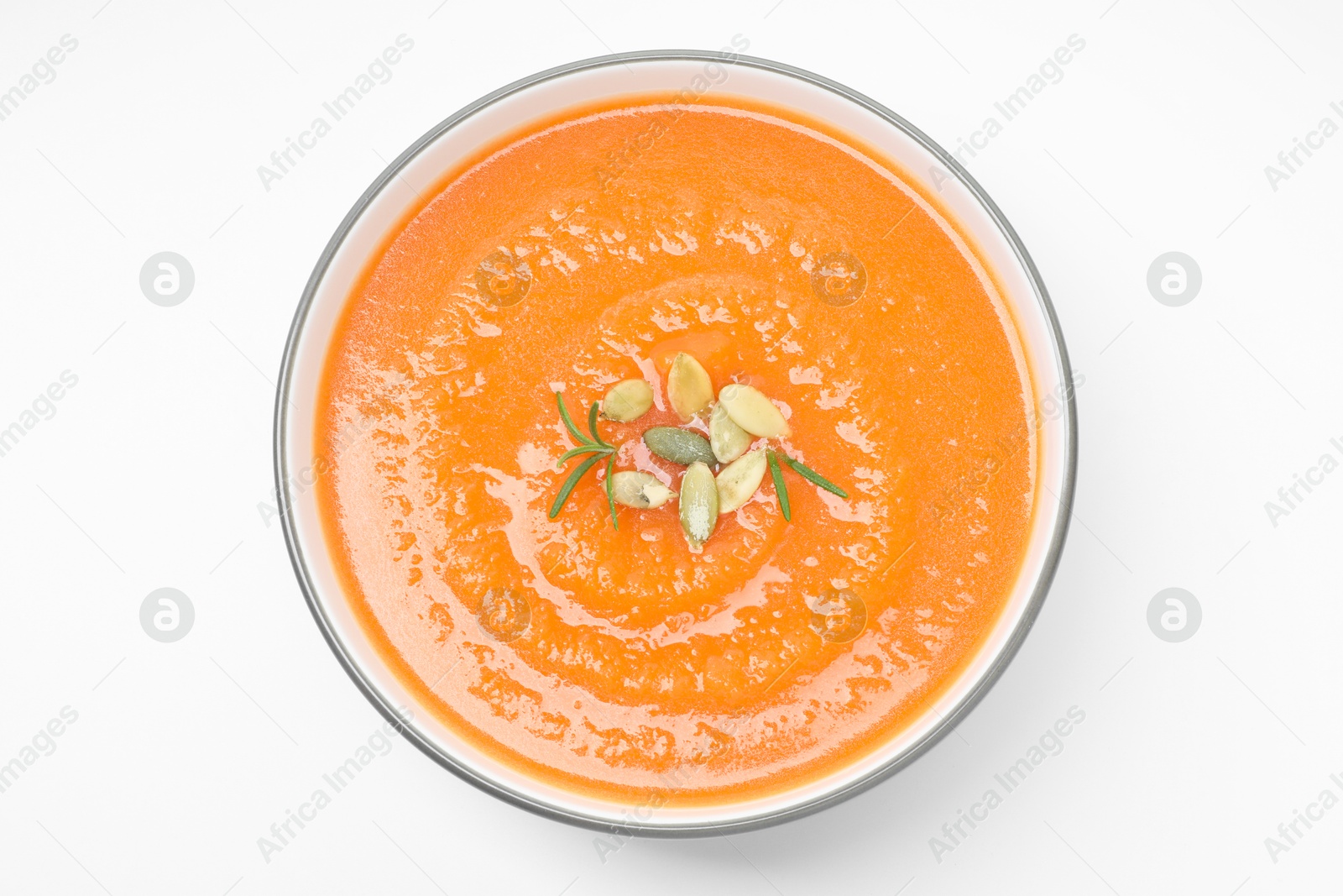 Photo of Delicious sweet potato soup with pumpkin seeds in bowl isolated on white, top view