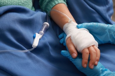 Photo of Doctor and child with IV drip in hospital, closeup