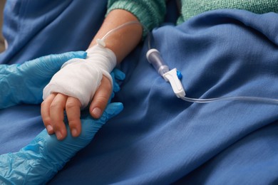 Photo of Doctor and child with IV drip in hospital, closeup