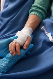 Photo of Doctor and child with IV drip in hospital, closeup