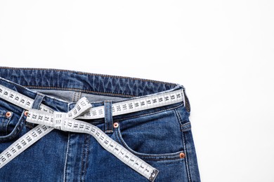 Photo of Jeans and measuring tape on white background, top view