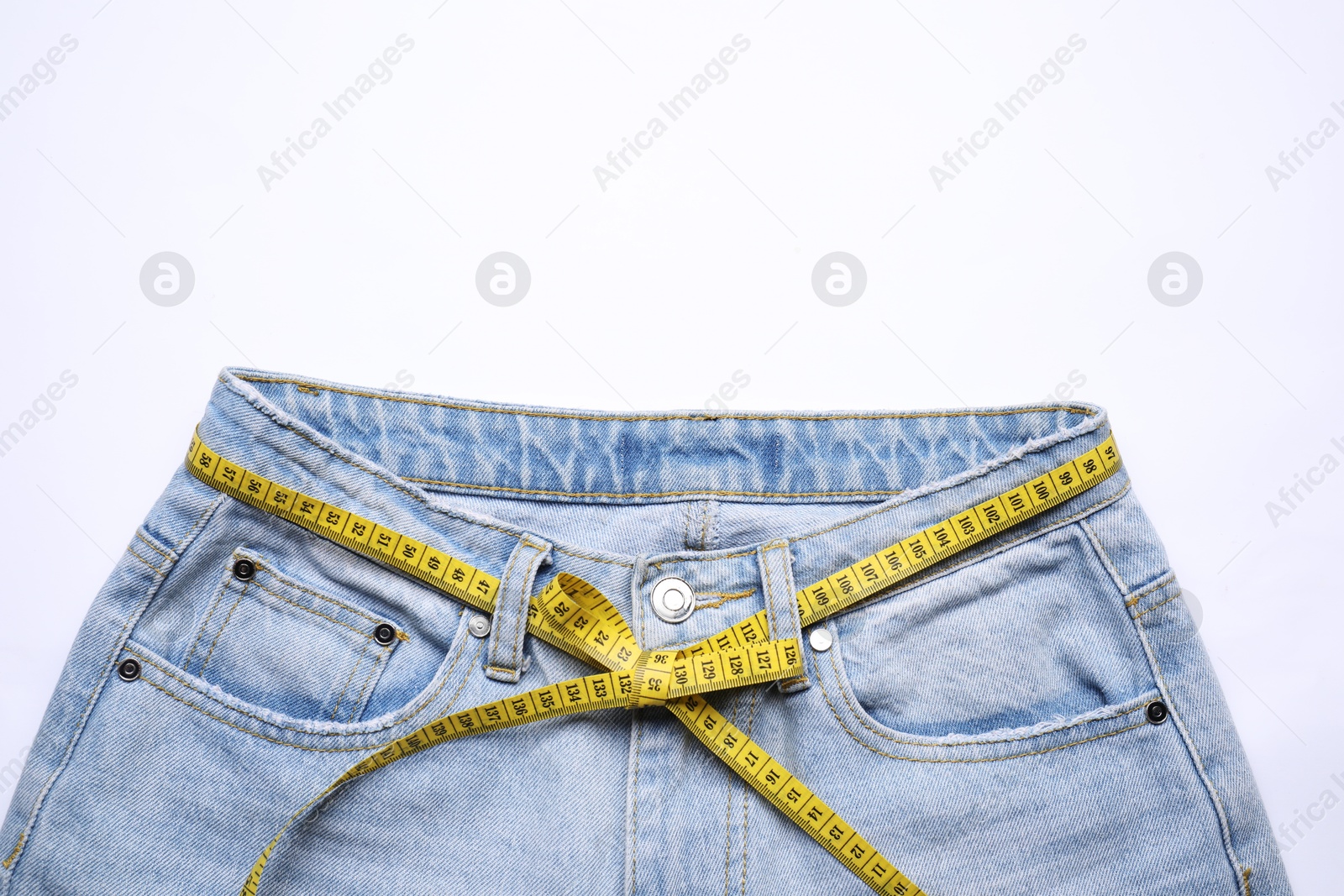 Photo of Jeans and measuring tape on white background, top view