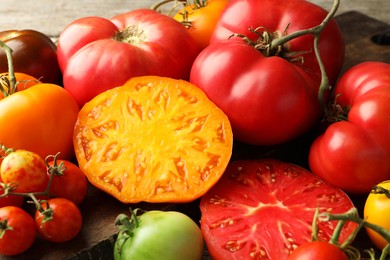 Photo of Many different ripe tomatoes on wooden table, closeup