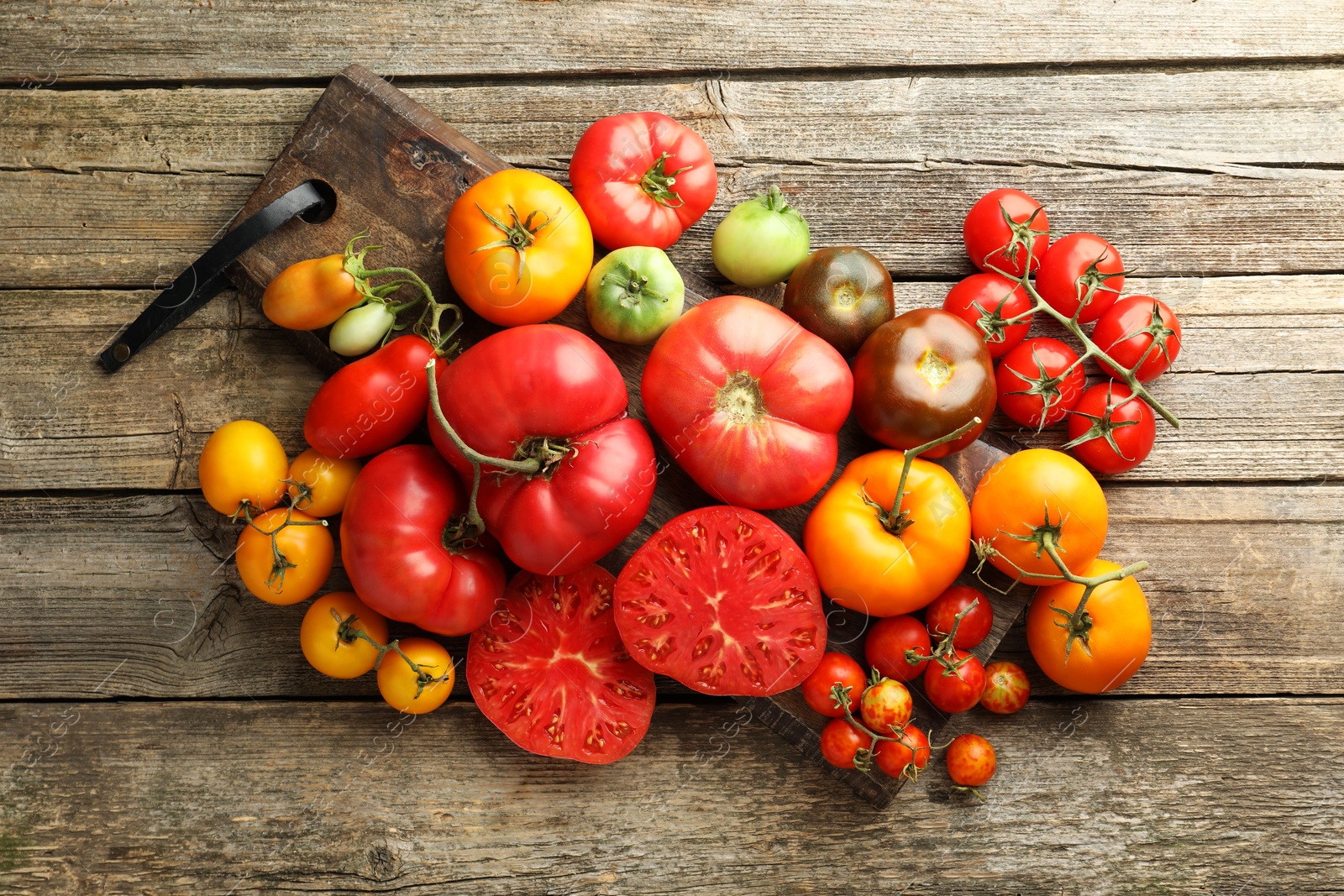 Photo of Different ripe tomatoes on wooden table, top view