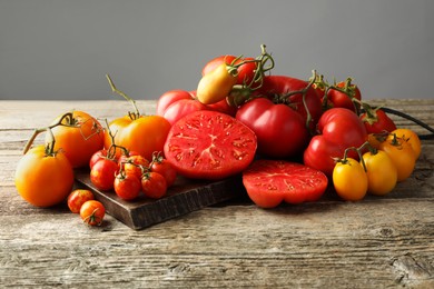 Many different ripe tomatoes on wooden table