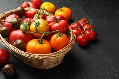 Photo of Basket with different ripe and unripe tomatoes on grey textured table