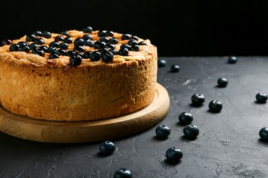 Photo of Delicious homemade blueberry pie and fresh berries on black table