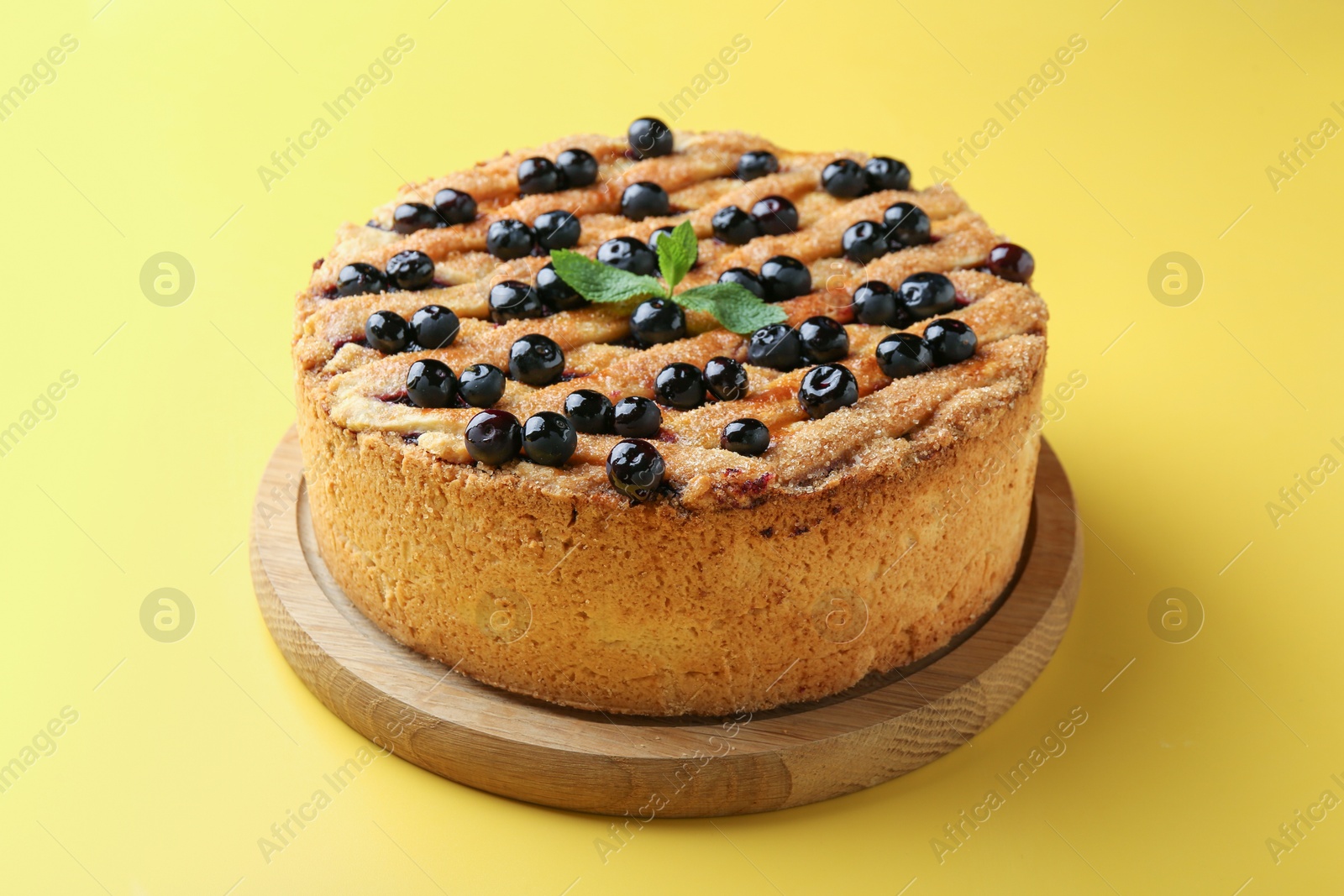 Photo of Delicious homemade blueberry pie with mint on yellow background