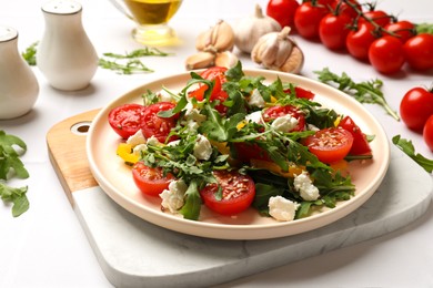 Photo of Tasty salad with arugula, cheese and vegetables on white table, closeup