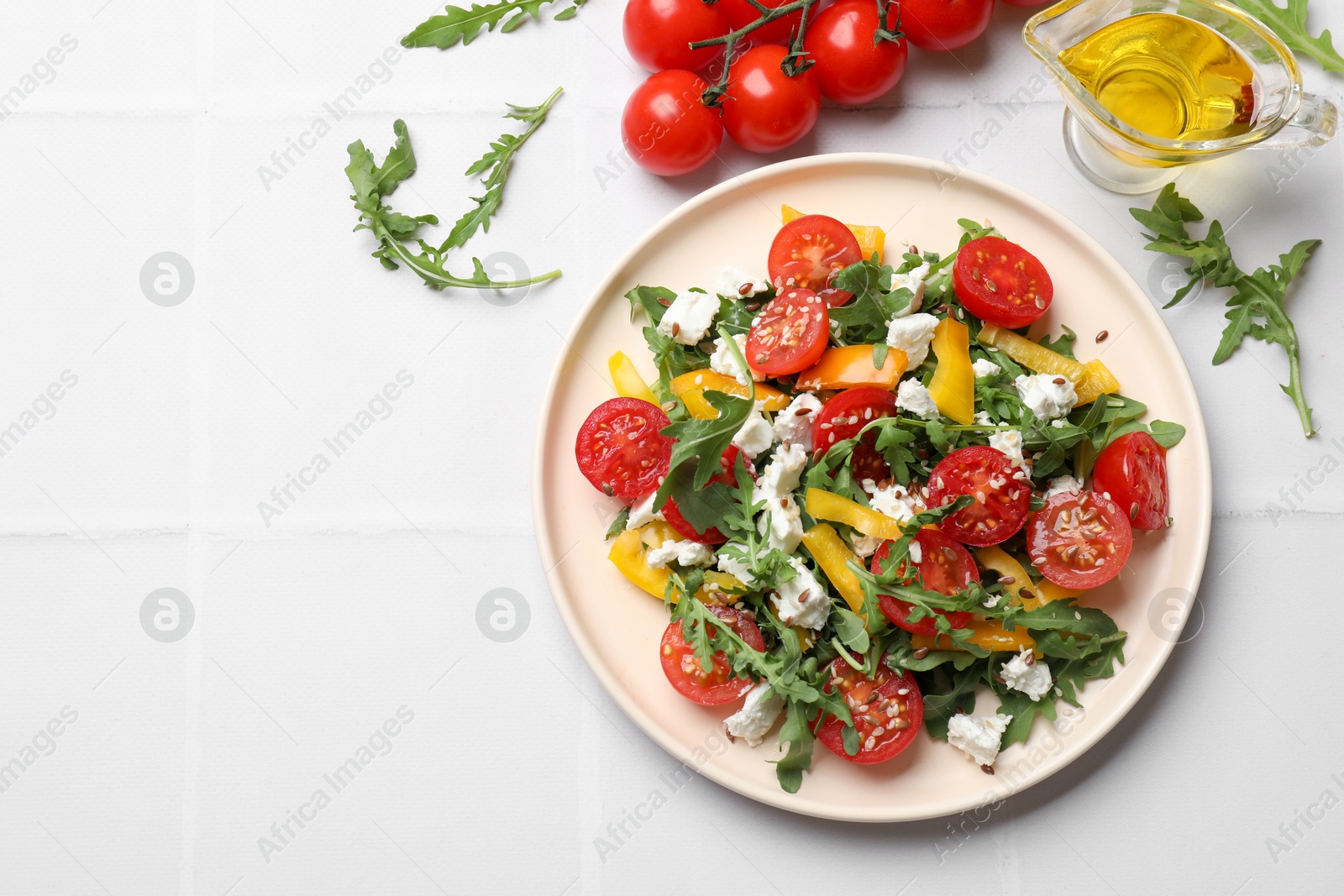 Photo of Tasty salad with arugula, cheese and vegetables on white tiled table, flat lay. Space for text